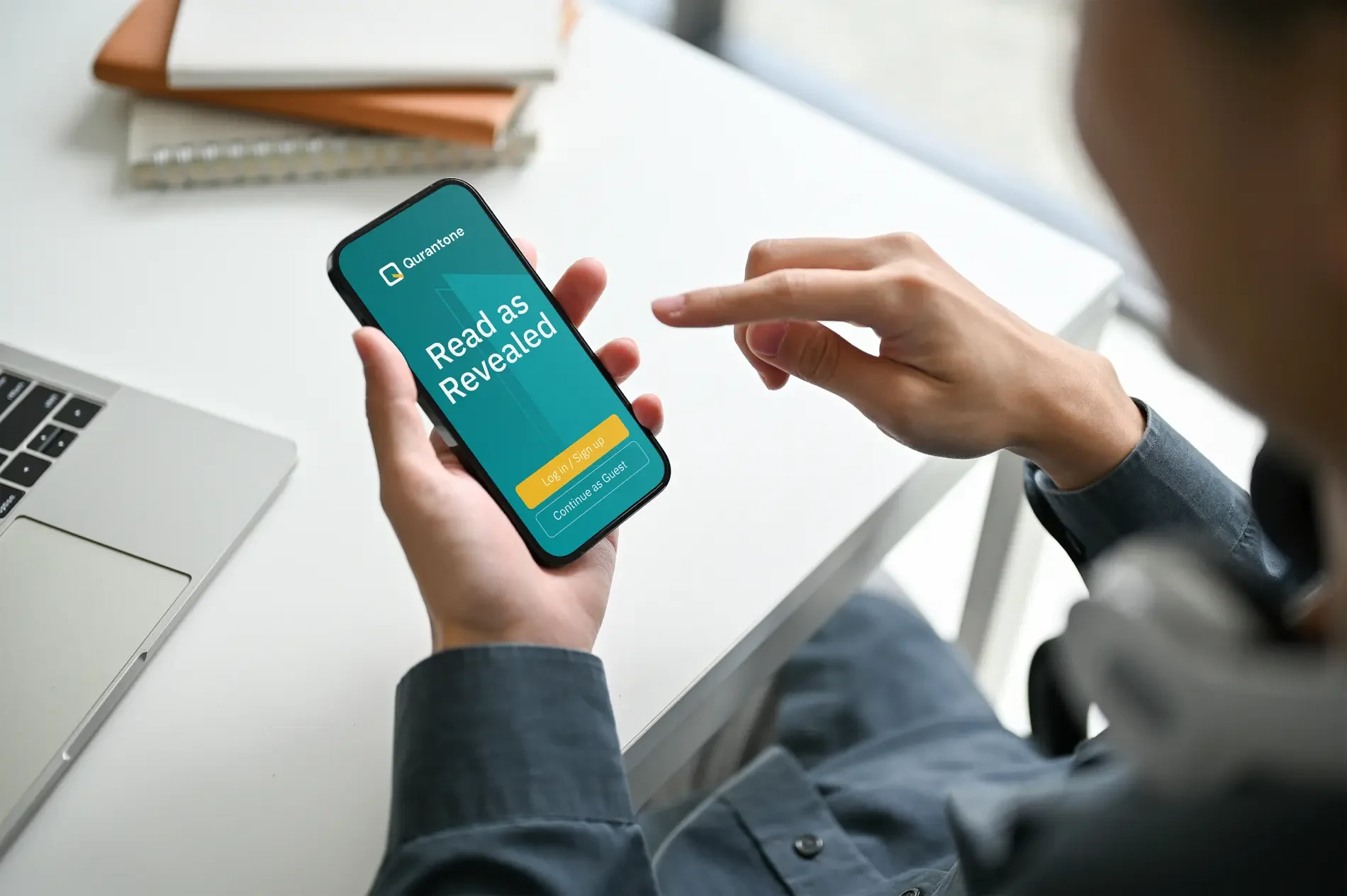 A hand holding a mobile phone displaying a large QR code on the screen.